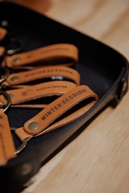 A set of leather keychains on a tray with the text 'Winter Session' and 'Made in Denver' embossed on them.