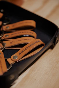 A selection of personalized coasters and keychains displayed on a rich leather surface.