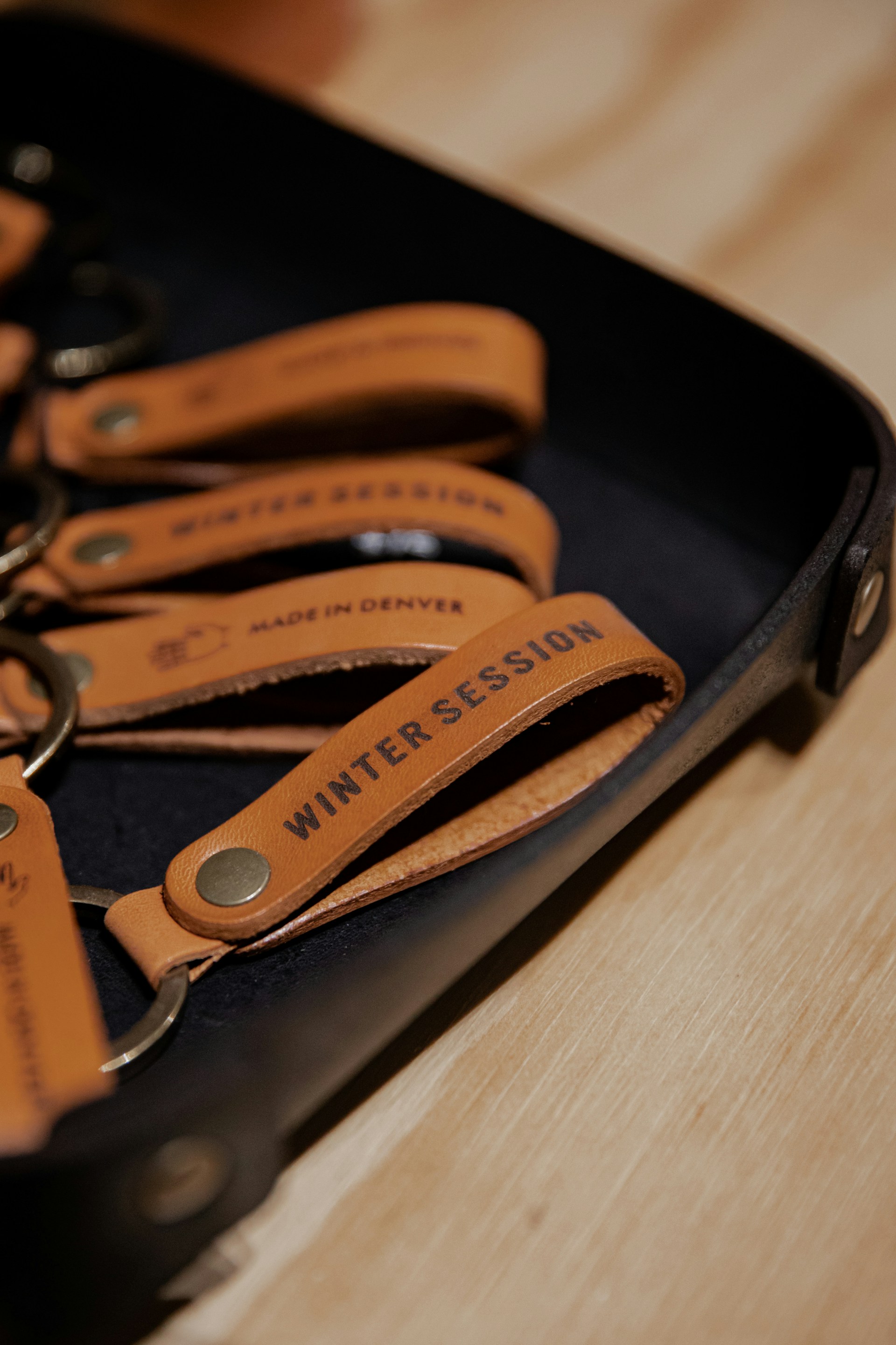 An assortment of custom laser-engraved leather keychains arranged artfully on a rustic wooden table.