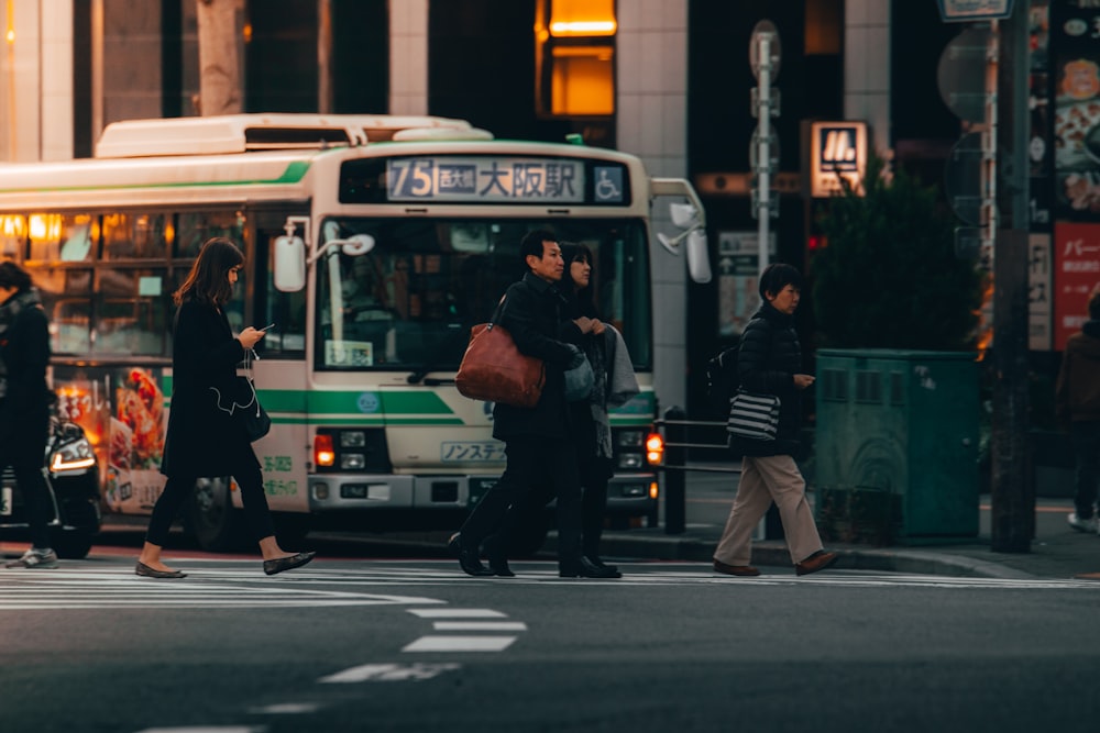 man in black jacket standing beside green and white bus during daytime