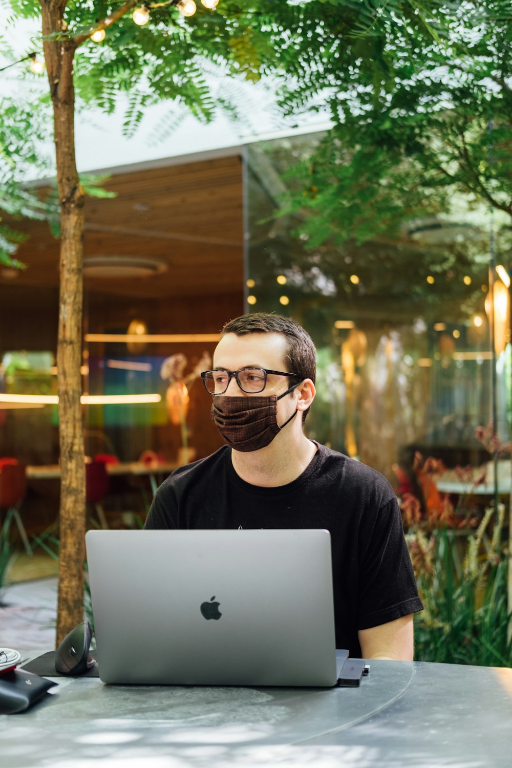 man in black crew neck t-shirt wearing black framed eyeglasses using silver macbook