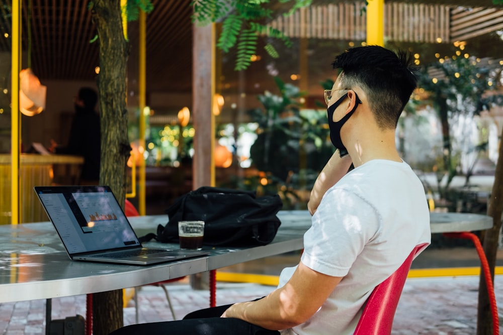 man in white t-shirt wearing black headphones sitting on chair