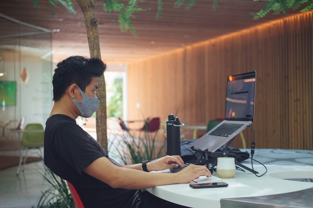 man in black t-shirt sitting in front of laptop computer