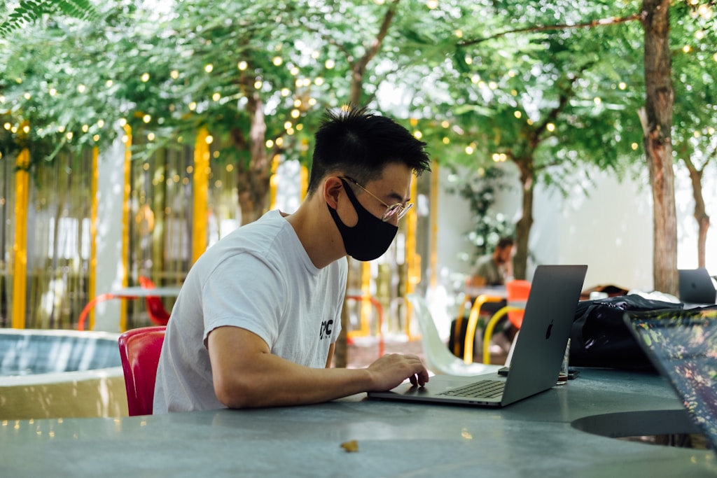 man in white crew neck t-shirt wearing black sunglasses using laptop computer