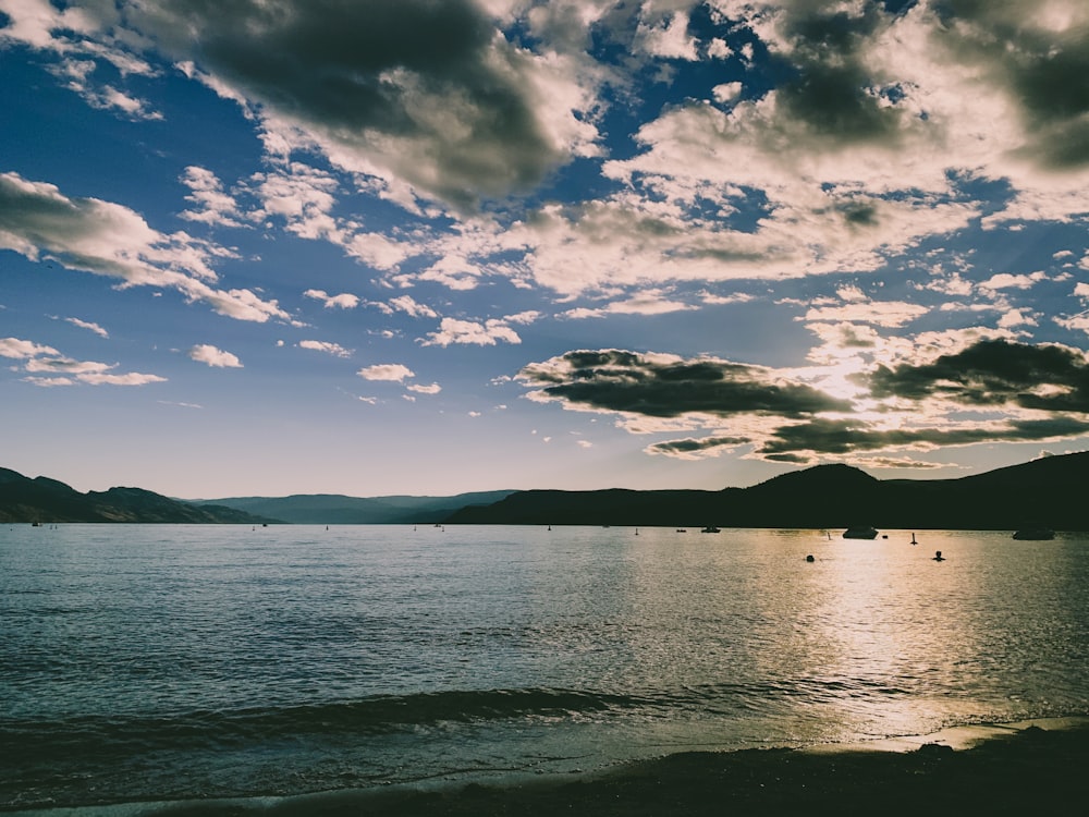 body of water under blue sky and white clouds during daytime