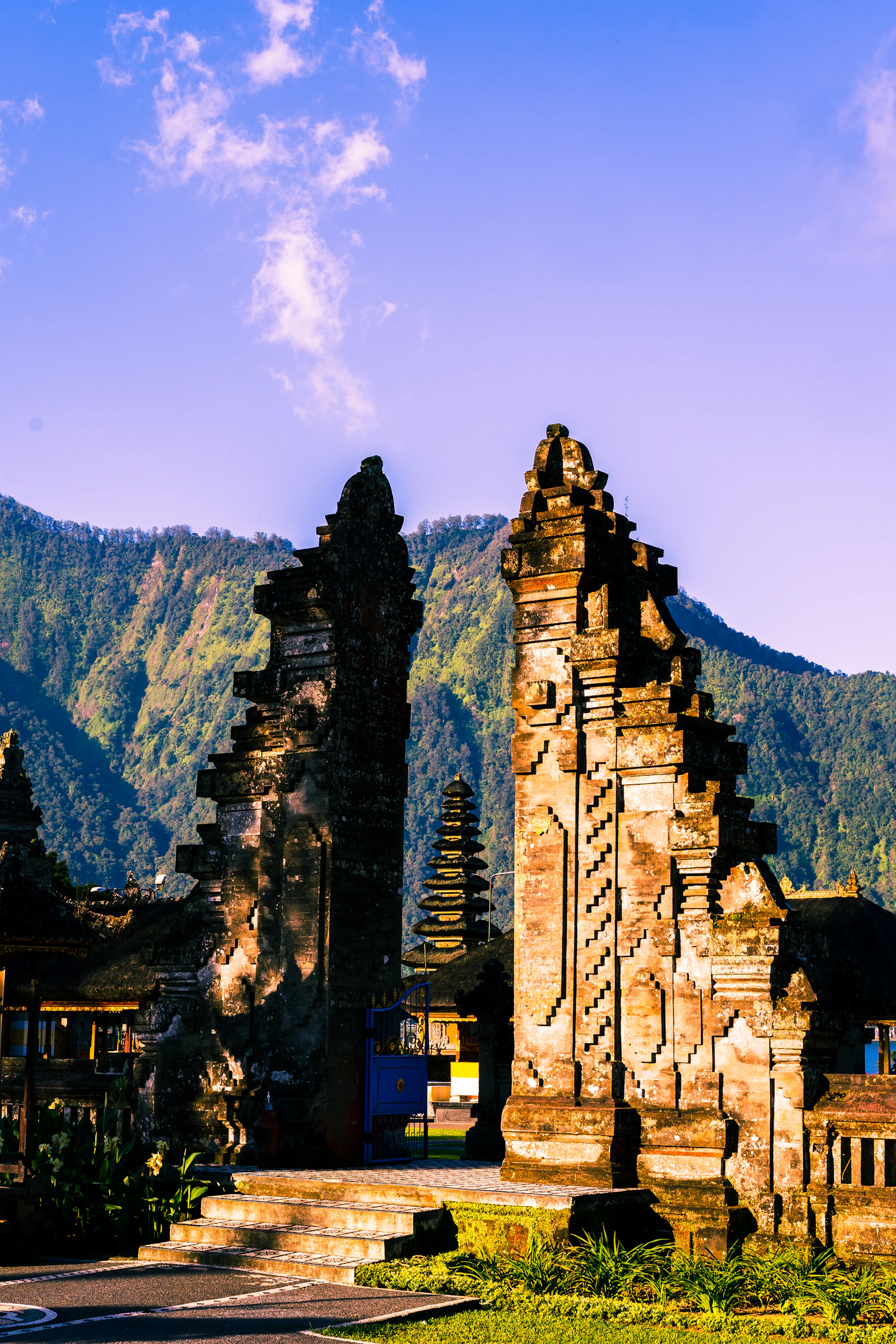 A carved Balinese temple gate in front of forested mountains
