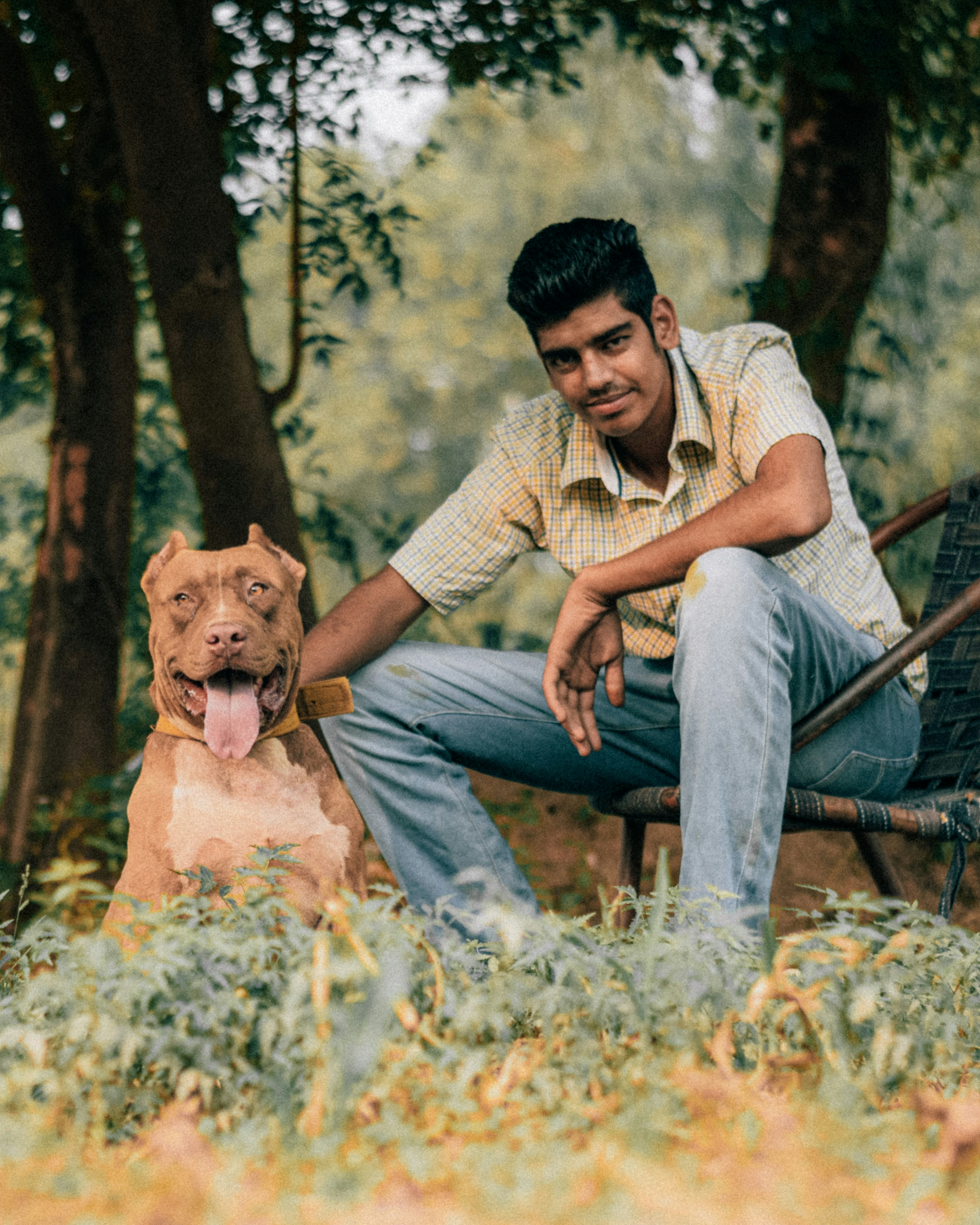 man in white and brown stripe dress shirt sitting beside brown short coated dog