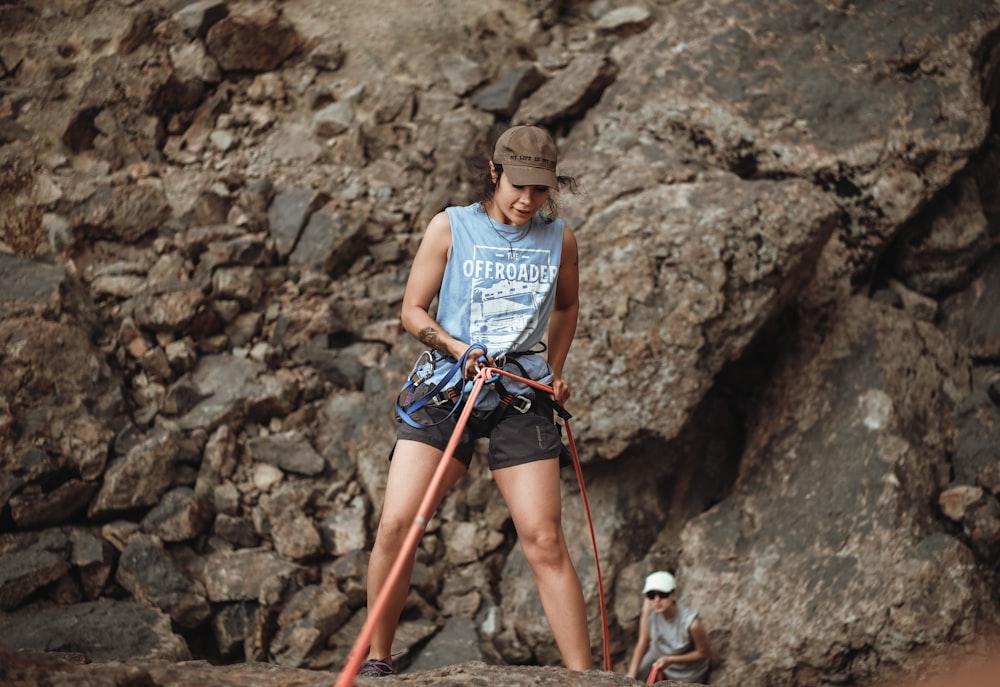 woman in white tank top and red shorts standing on rocky mountain during daytime