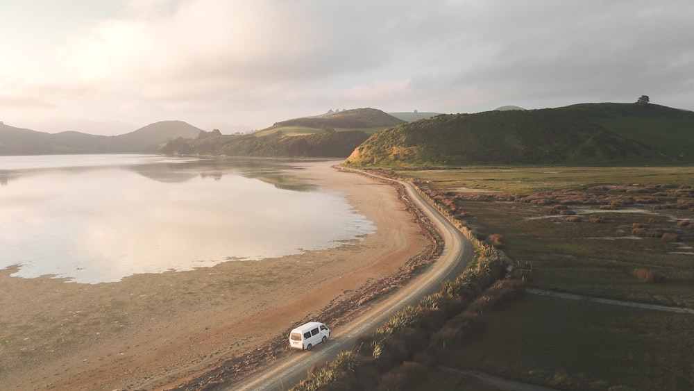 Coche blanco en la carretera cerca del cuerpo de agua durante el día