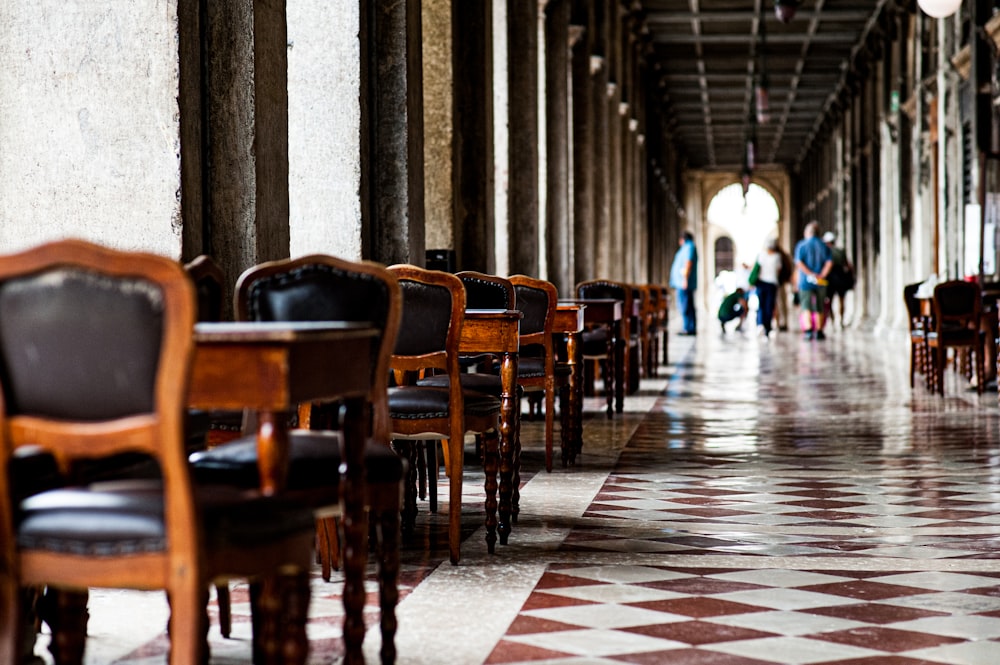 a row of wooden chairs sitting on top of a checkered floor