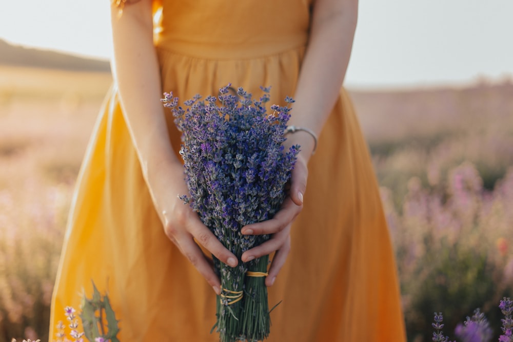 woman in yellow dress holding purple flower bouquet