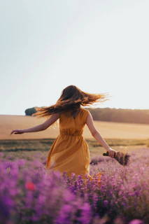 woman in yellow dress standing on purple flower field during daytime
