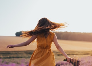 woman in yellow dress standing on purple flower field during daytime