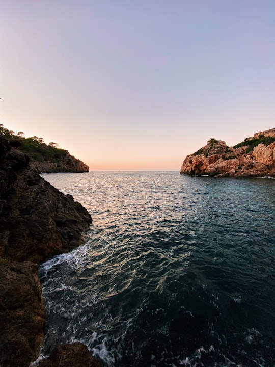brown rock formation beside body of water during daytime in Islas Baleares Spain