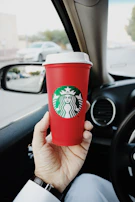 Close-up of a client’s hand holding a coffee cup inside a luxury car.