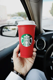 Close-up of a client’s hand holding a coffee cup inside a luxury car.
