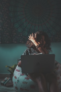 An adult student lounging with a cheeky smile, laptop open, surrounded by books and notes, embodying relaxed confidence.
