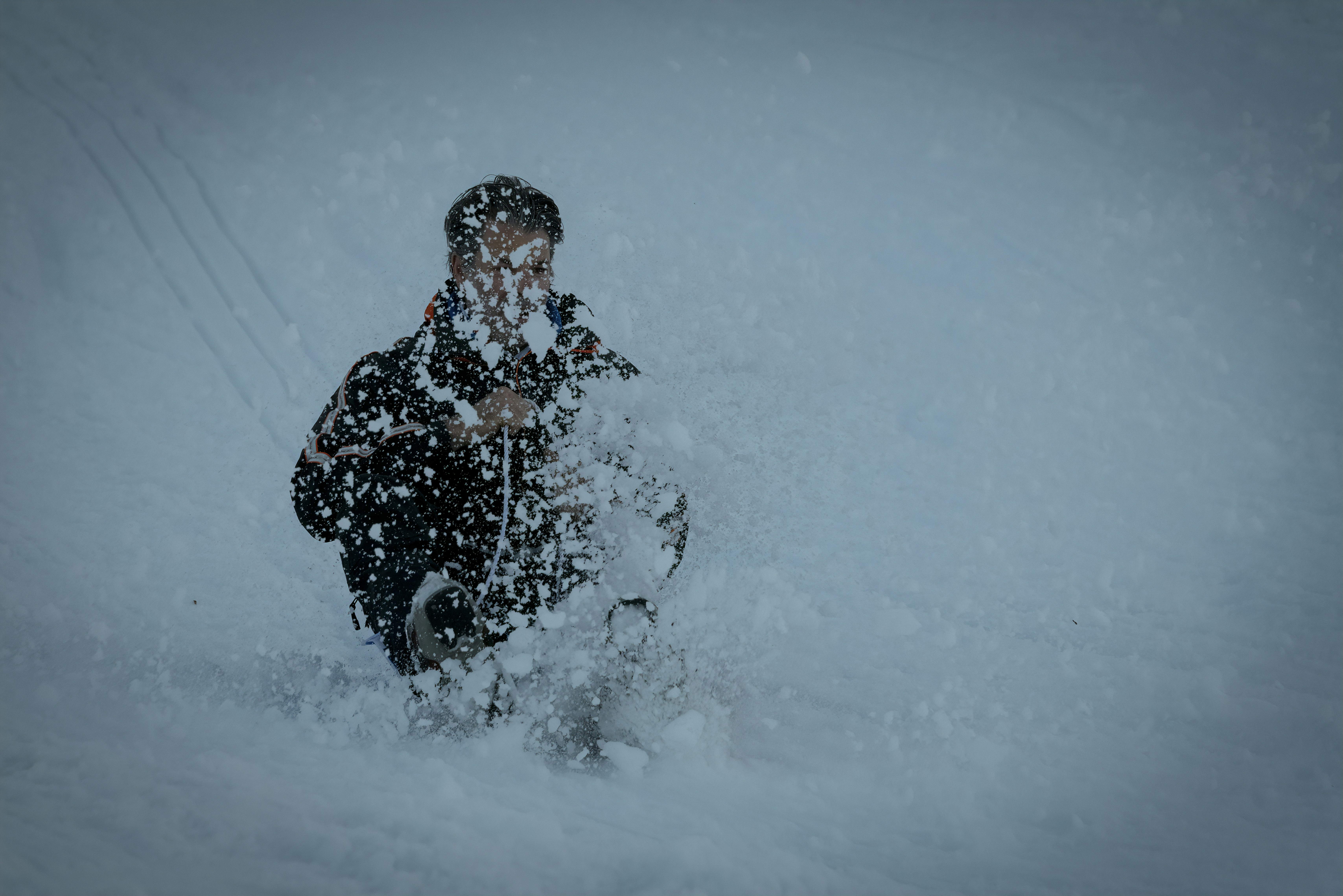 woman in black jacket and black pants standing on snow covered ground during daytime toboggan teams background