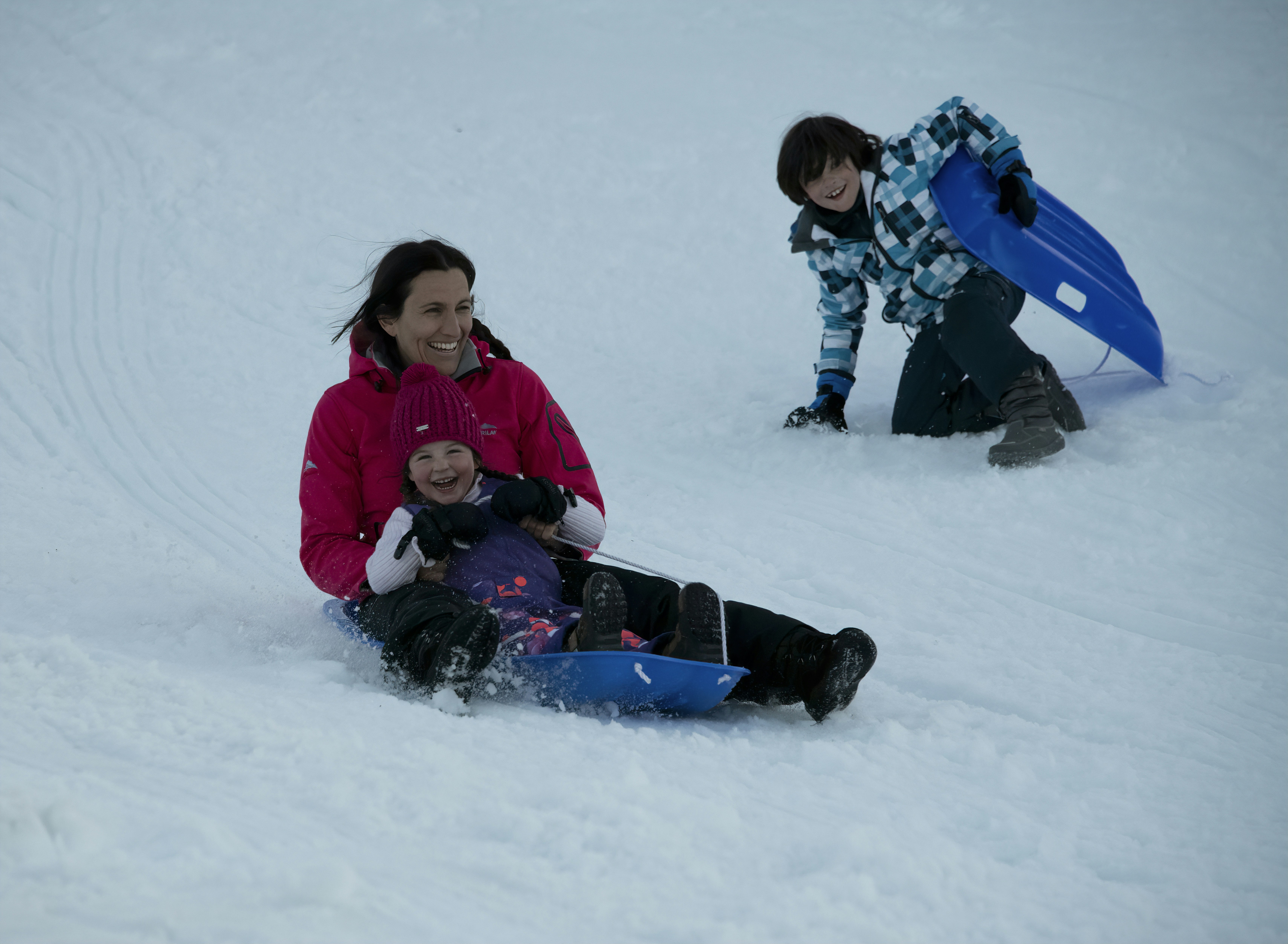 girl in pink jacket playing on snow toboggan teams background