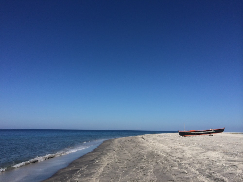 red and black metal bench on beach shore during daytime