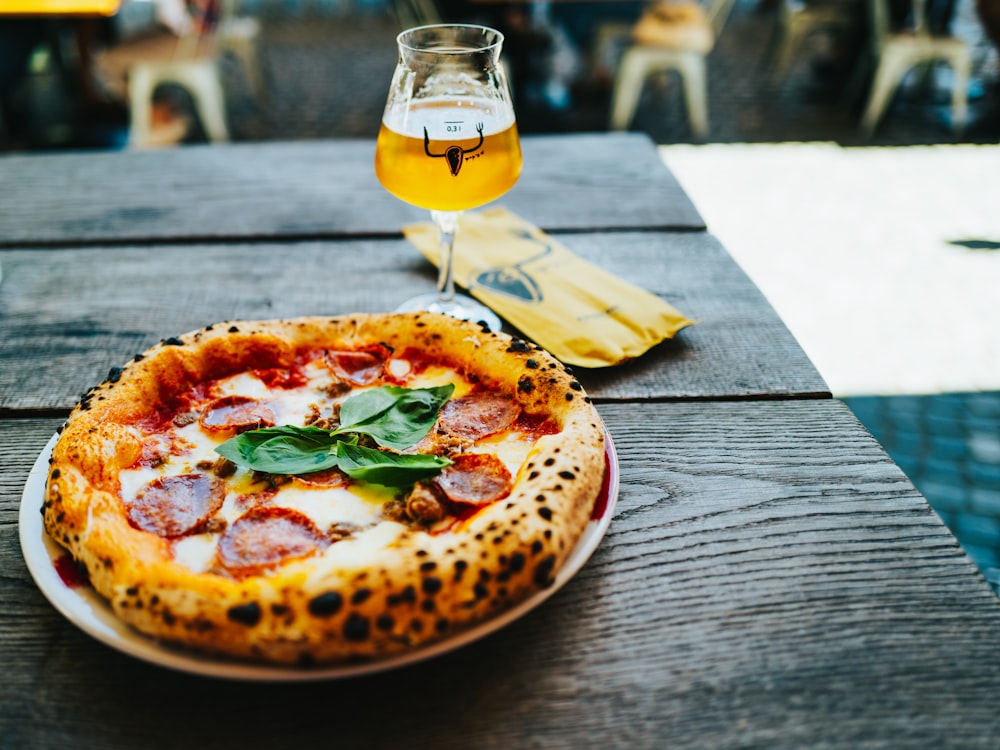 pizza with green leaf and yellow liquid on brown wooden table