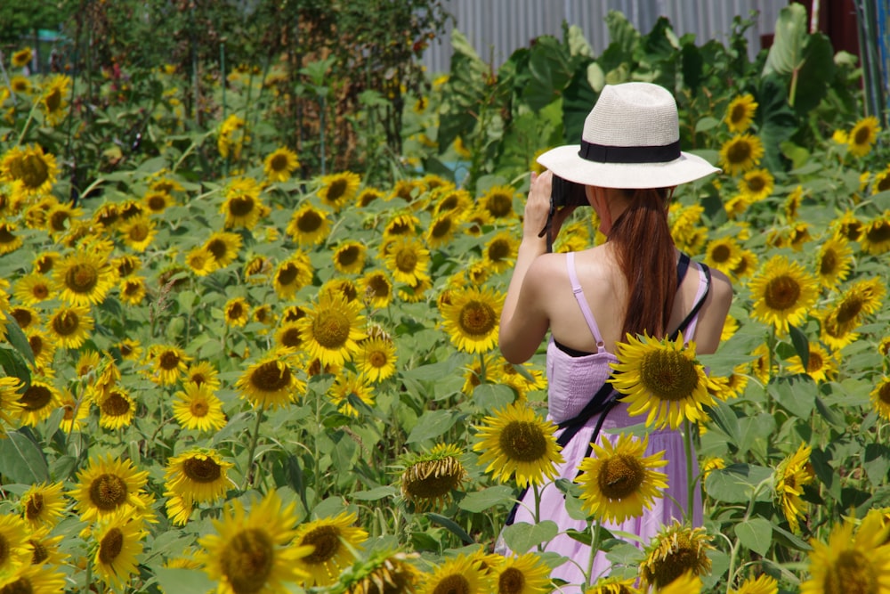 woman in black tank top and white sun hat standing on sunflower field during daytime
