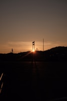 A sunset shot capturing the silhouette of a major infrastructure project with mountains in the background.