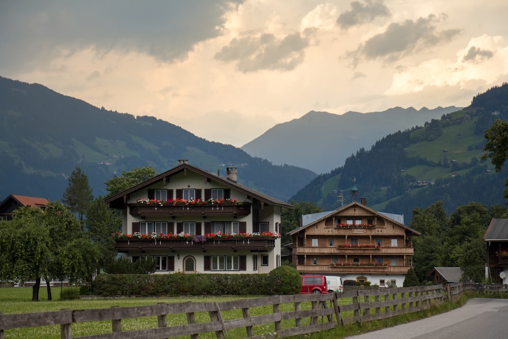 brown and white wooden house near green grass field and mountain during daytime