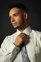 A candid shot of a man adjusting his collar, showcasing a subtle, refined grooming routine.