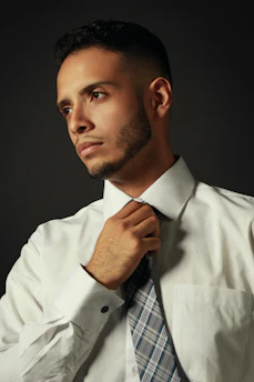 A candid shot of a man adjusting his collar, showcasing a subtle, refined grooming routine.
