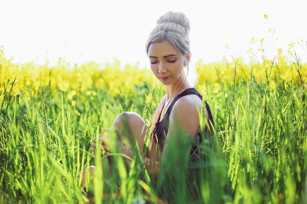 woman in black tank top standing on yellow flower field during daytime