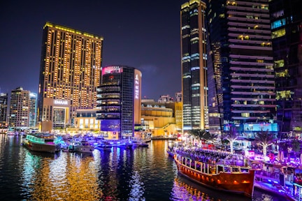 brown boat on water near high rise buildings during night time