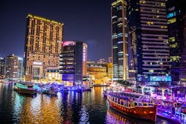brown boat on water near high rise buildings during night time