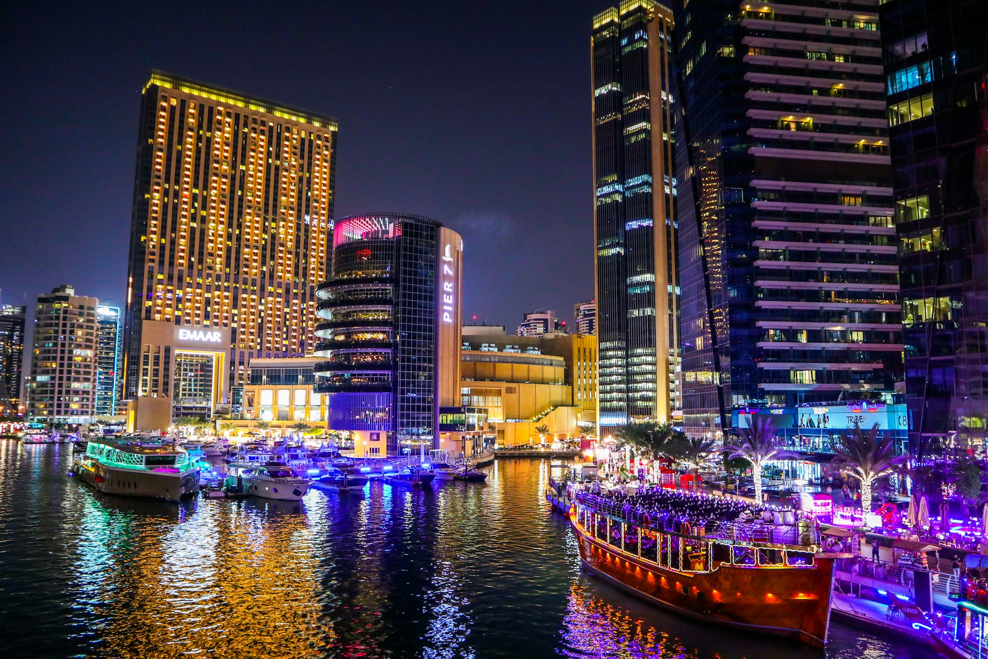 brown boat on water near high rise buildings during night time