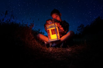 A dreamy child surrounded by glowing lanterns in a nighttime garden.