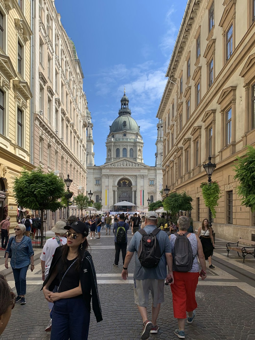 people walking on sidewalk near white concrete building during daytime