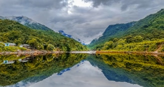 green mountain beside body of water under cloudy sky during daytime