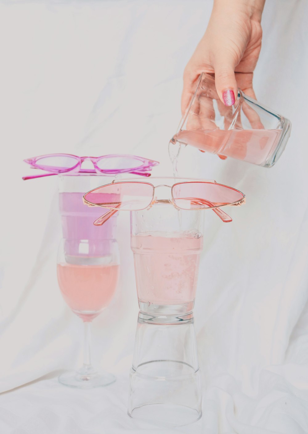 person holding clear drinking glass with pink liquid