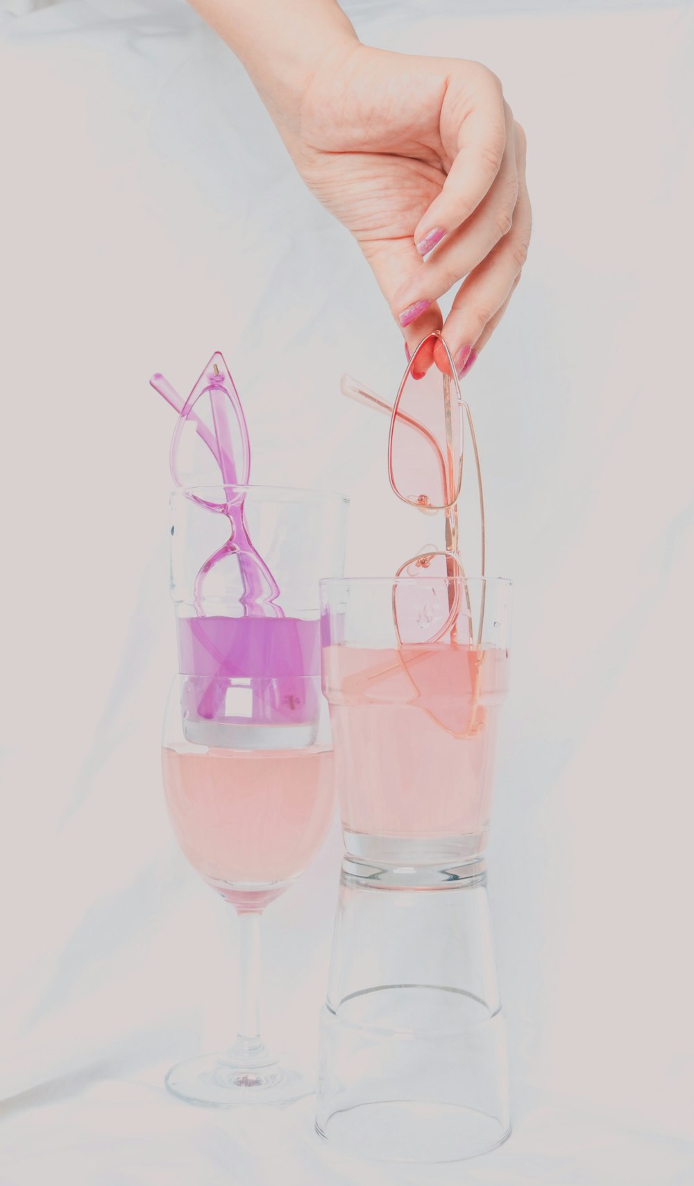 persona sosteniendo un vaso transparente con líquido rosado