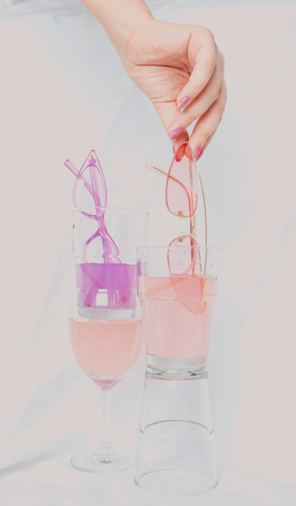 person holding clear drinking glass with pink liquid