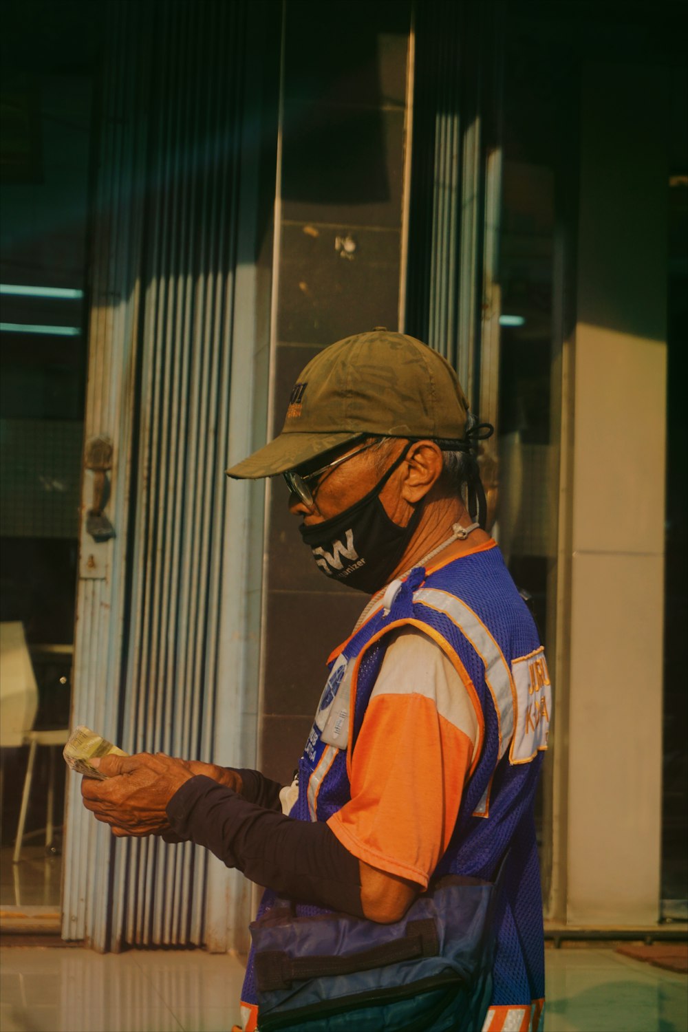 homme en chemise à manches longues bleu et orange portant un chapeau marron