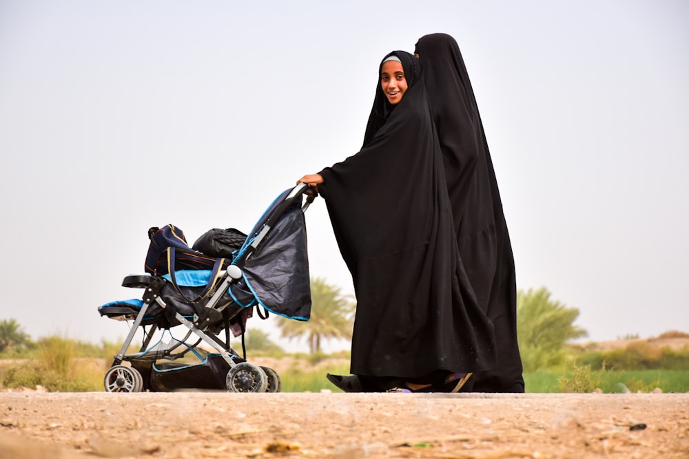 woman in black hijab standing on brown field during daytime