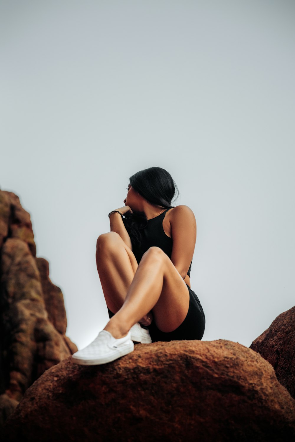 woman in black bikini sitting on brown rock during daytime