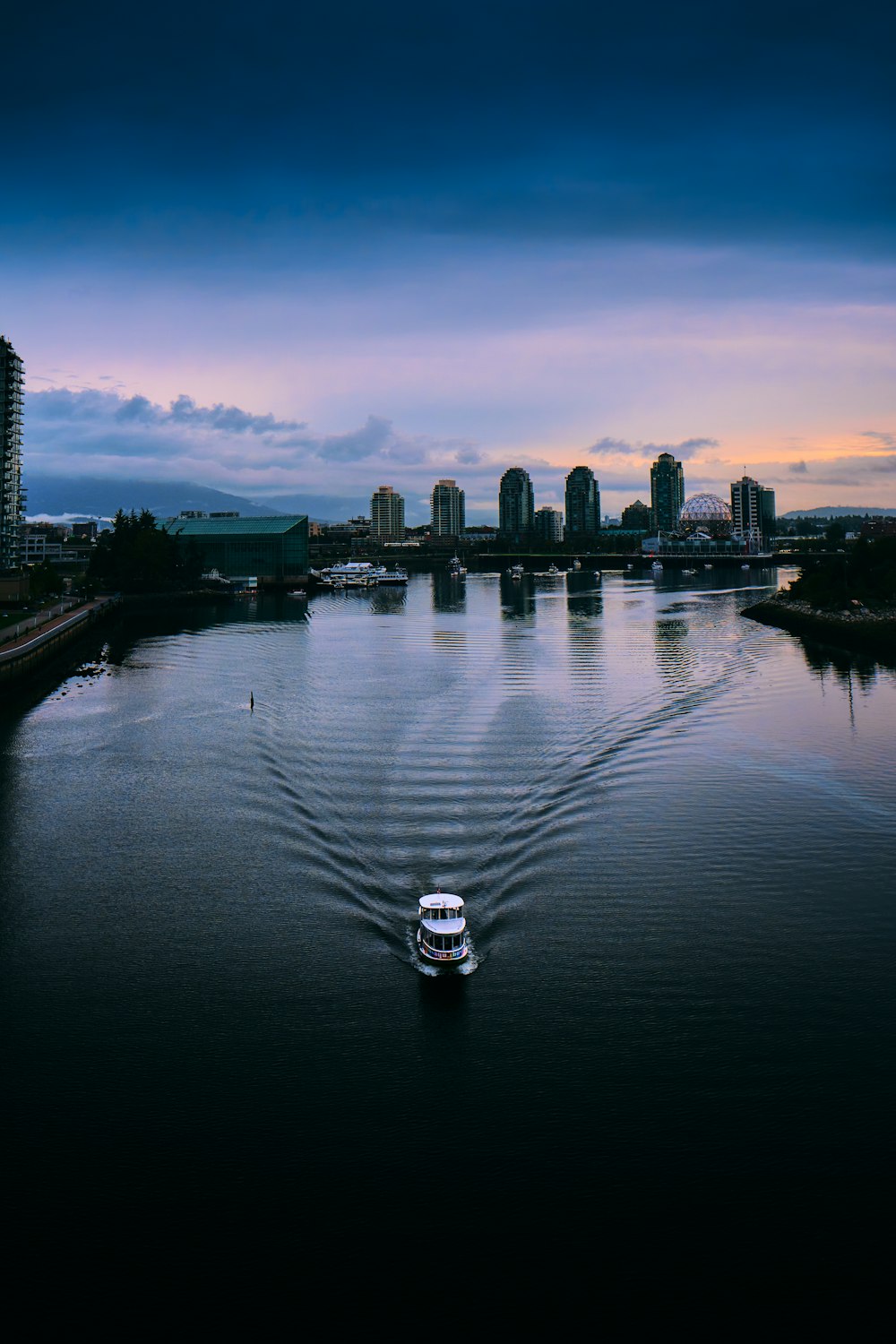 white boat on water near city buildings during night time