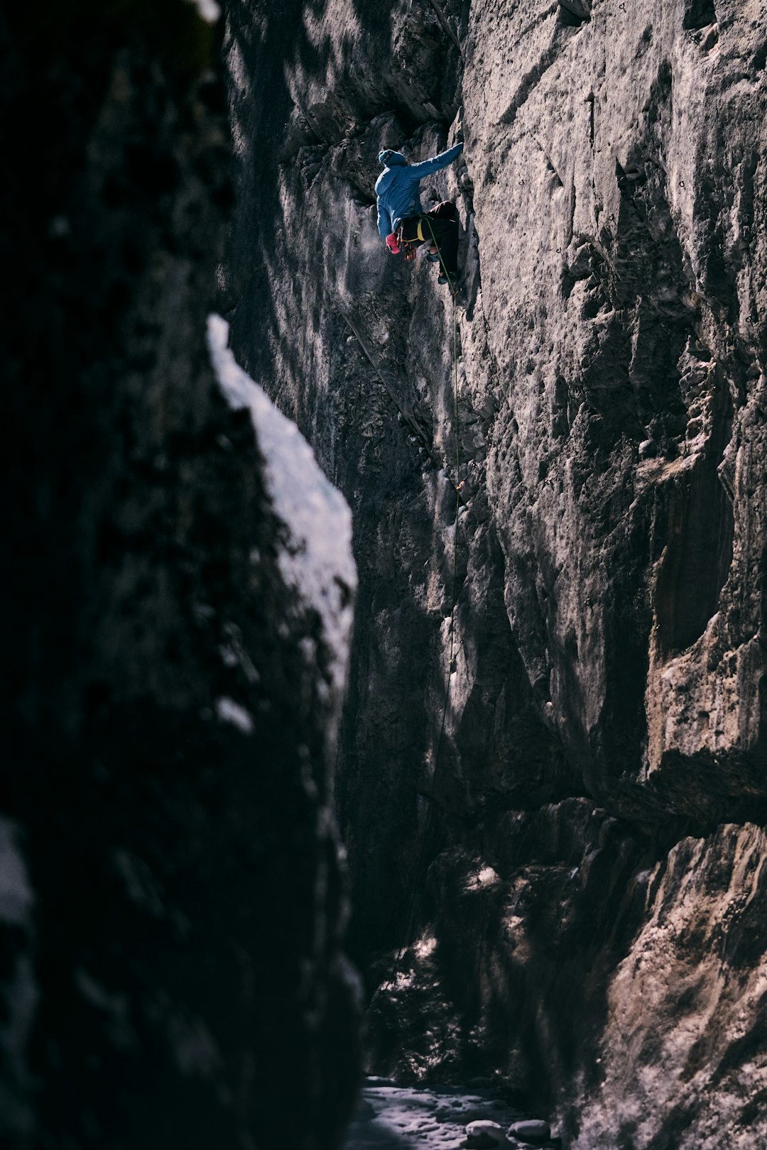 person in blue jacket climbing on rocky mountain during daytime