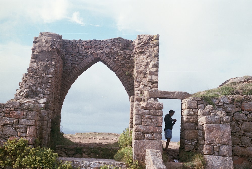 man in black shirt standing on brown arch during daytime