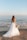 woman in white wedding dress standing on beach during daytime