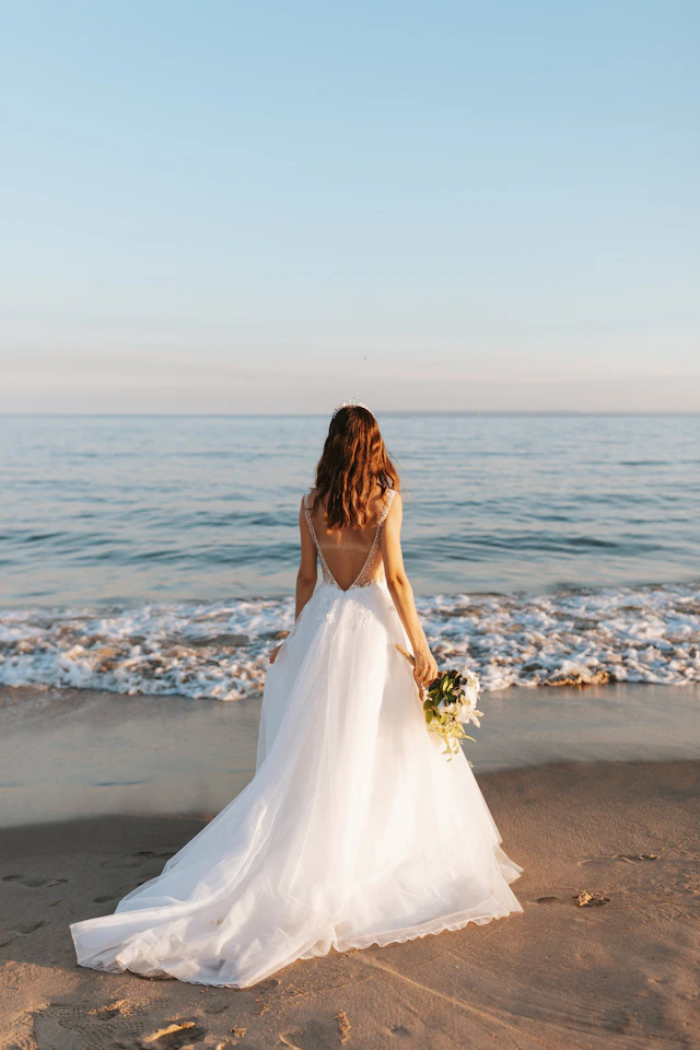 Novia de espaldas frente al mar, con vestido de espalda descubierta