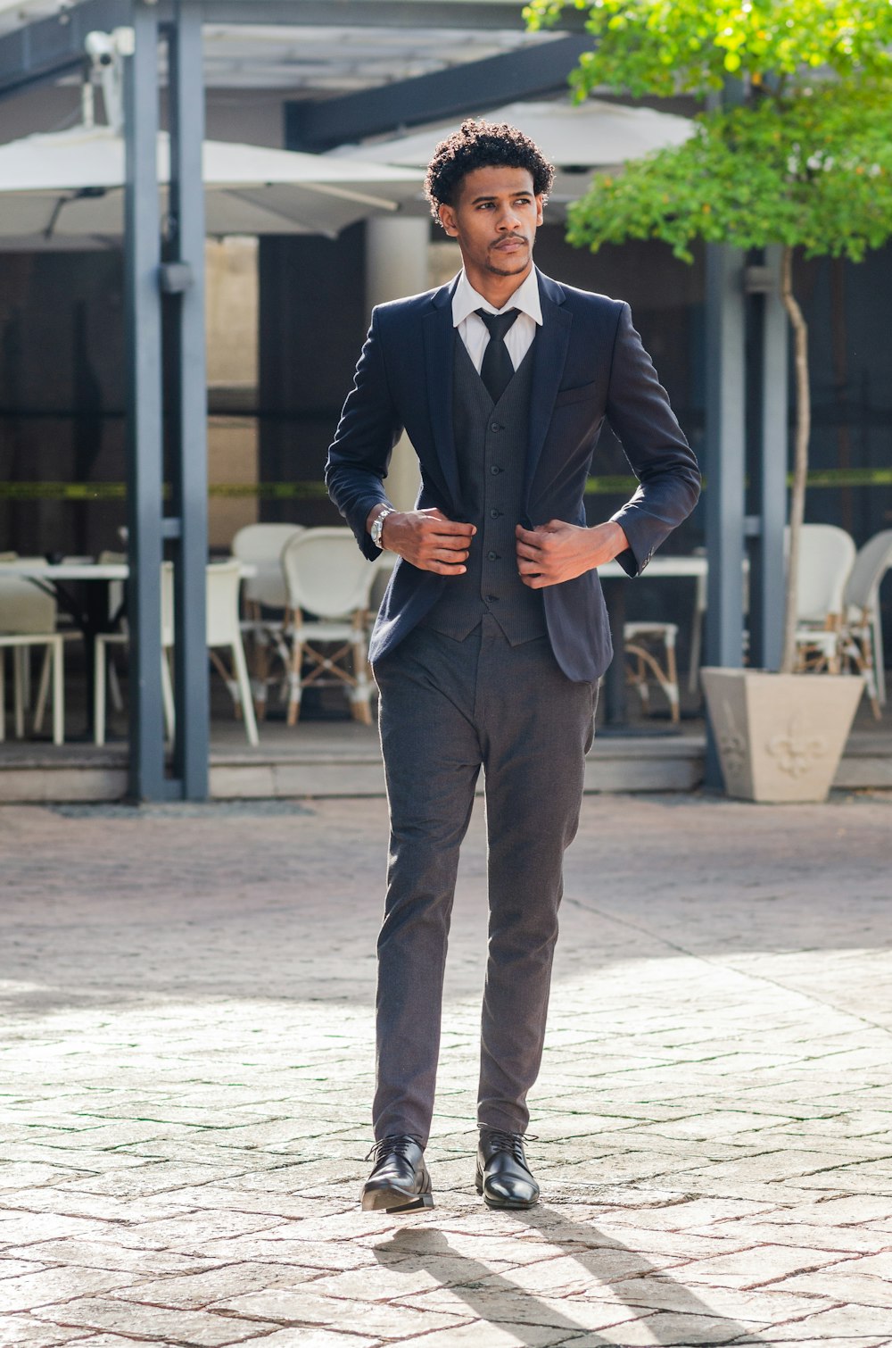 man in black suit standing on white floor