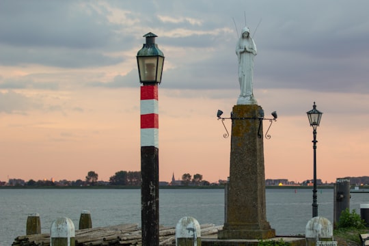 black and red lighthouse near body of water during daytime in Volendam Netherlands